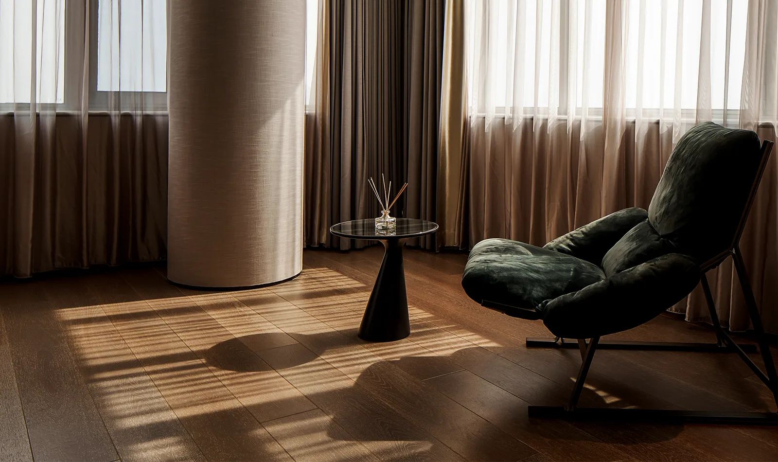 Light-filled lounge interior with a green armchair and wooden floor